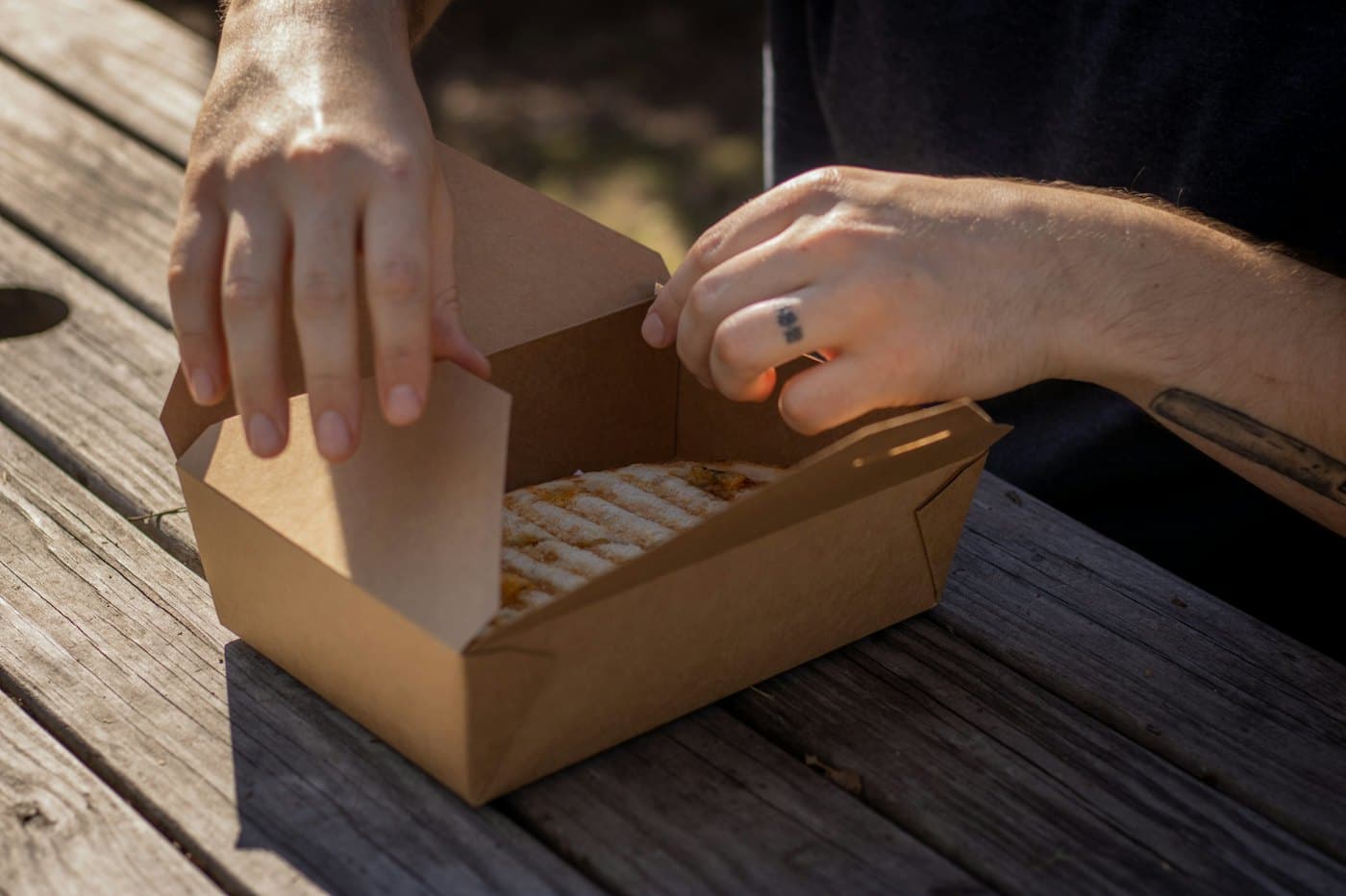 Hands folding a kraft bakery box